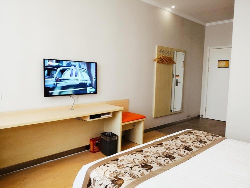 Habitación con cama y TV en la pared. en 7Days Inn Yulin south gate bus station, en Yulin