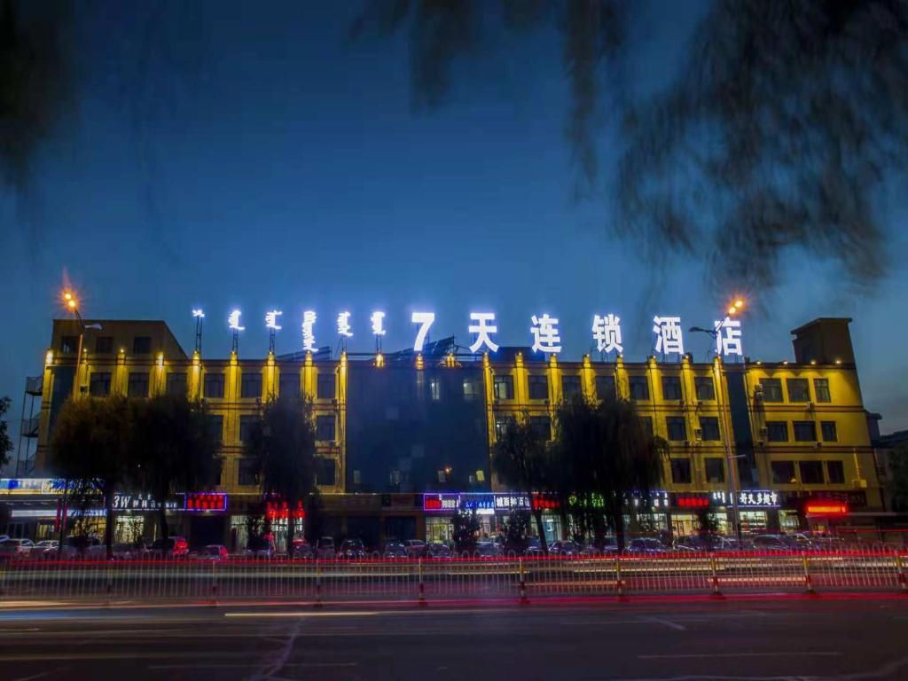 un gran edificio amarillo con luces encendidas por la noche en 7Days Inn Tongliao Civil Aviation Road en Tongliao