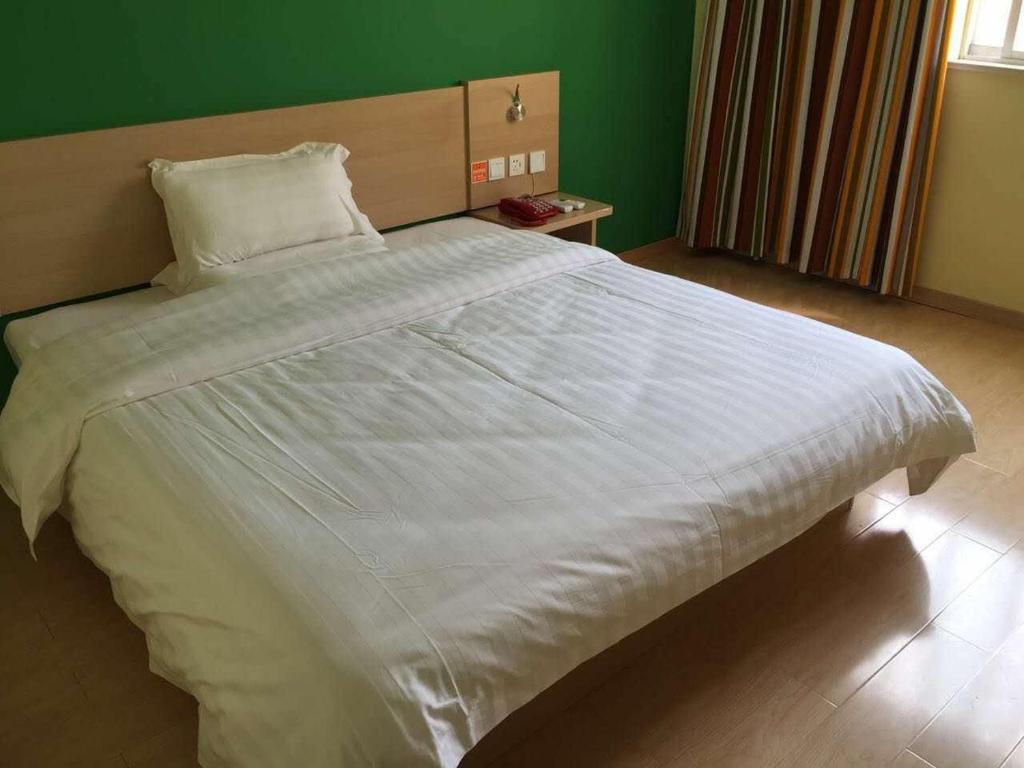 uma grande cama branca num quarto com uma parede verde em 7Days Inn Jintan passenger terminal em Changzhou