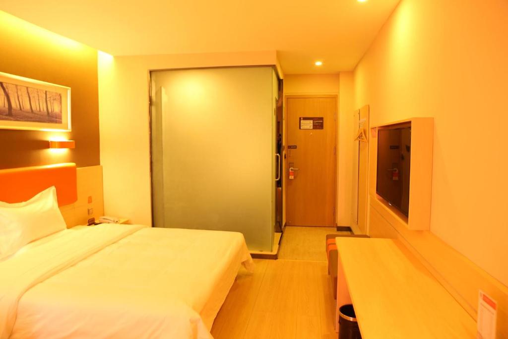 a hotel room with a bed and a sliding door at 7Days Premium Shihezi Recreation Plaza Merino Museum in Shihezi