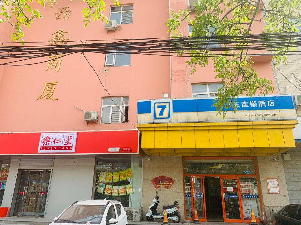 różowy budynek z żółtym i niebieskim znakiem w obiekcie 7Days Inn 261 Shijiazhuang Zhonghua Street New Railway Station w mieście Shijiazhuang
