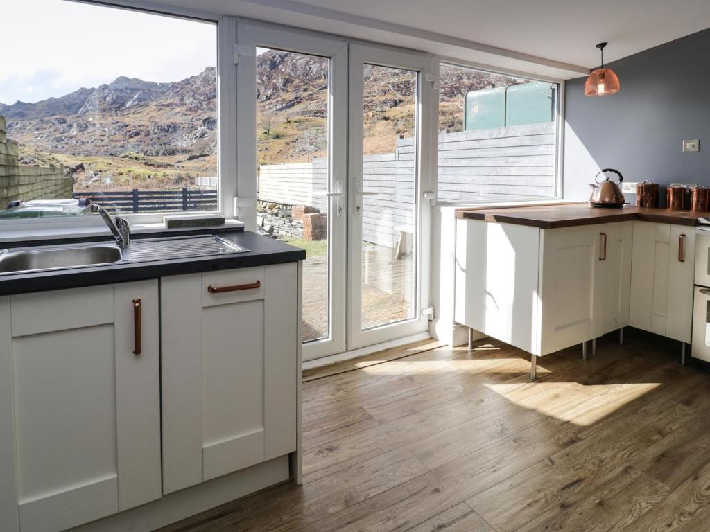 Una cocina con gabinetes blancos y una ventana grande. en 19 Cwmorthin Road, en Blaenau Ffestiniog