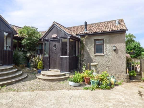 a small house with a wooden door and some plants at The Old Parlour in Winford