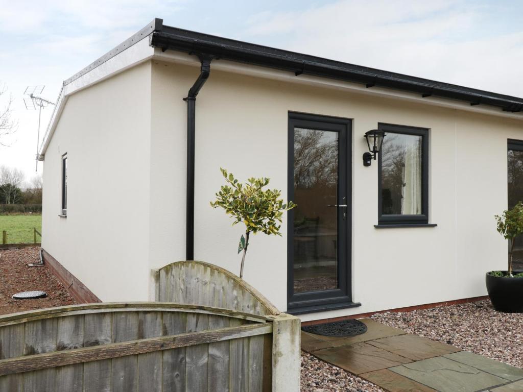 a white house with black windows and a fence at The Goose Shed in Thornton