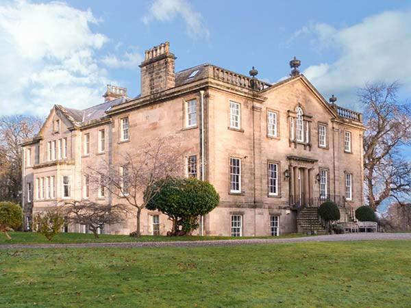 a large brick building with a grass field in front of it at Dalvey House in Forres