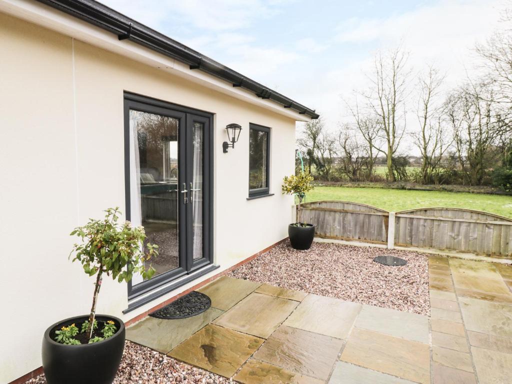 a home with a patio with two potted plants at The Old Stables in Thornton