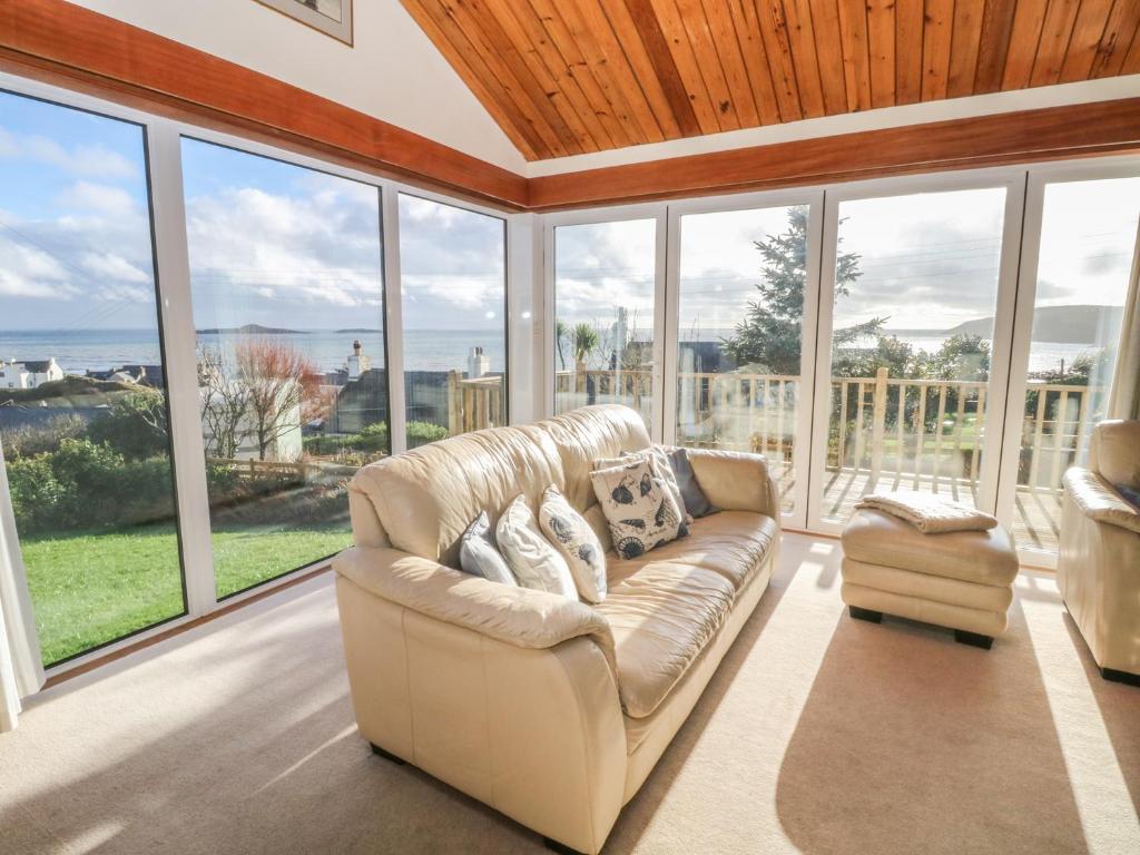 a living room with a couch and large windows at Paham in Aberdaron