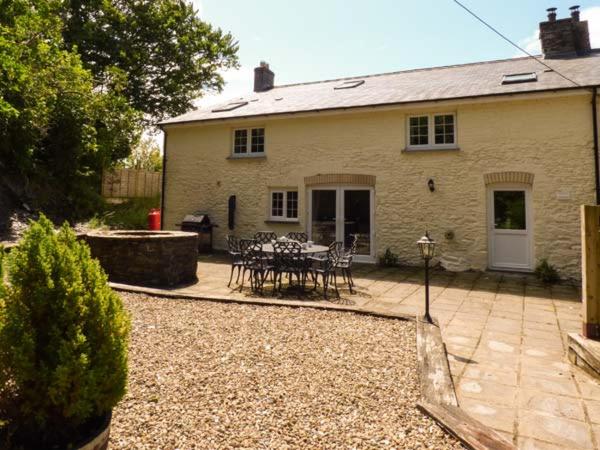 a house with a patio with a table and chairs at Penuwch Fach in Llanfihangel-y-creuddyn