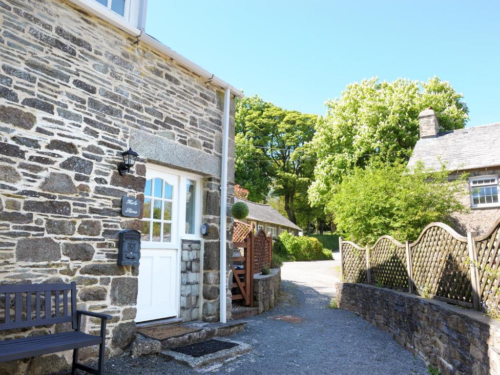 een stenen huisje met een bank ervoor bij Hele Stone Cottage in Launceston