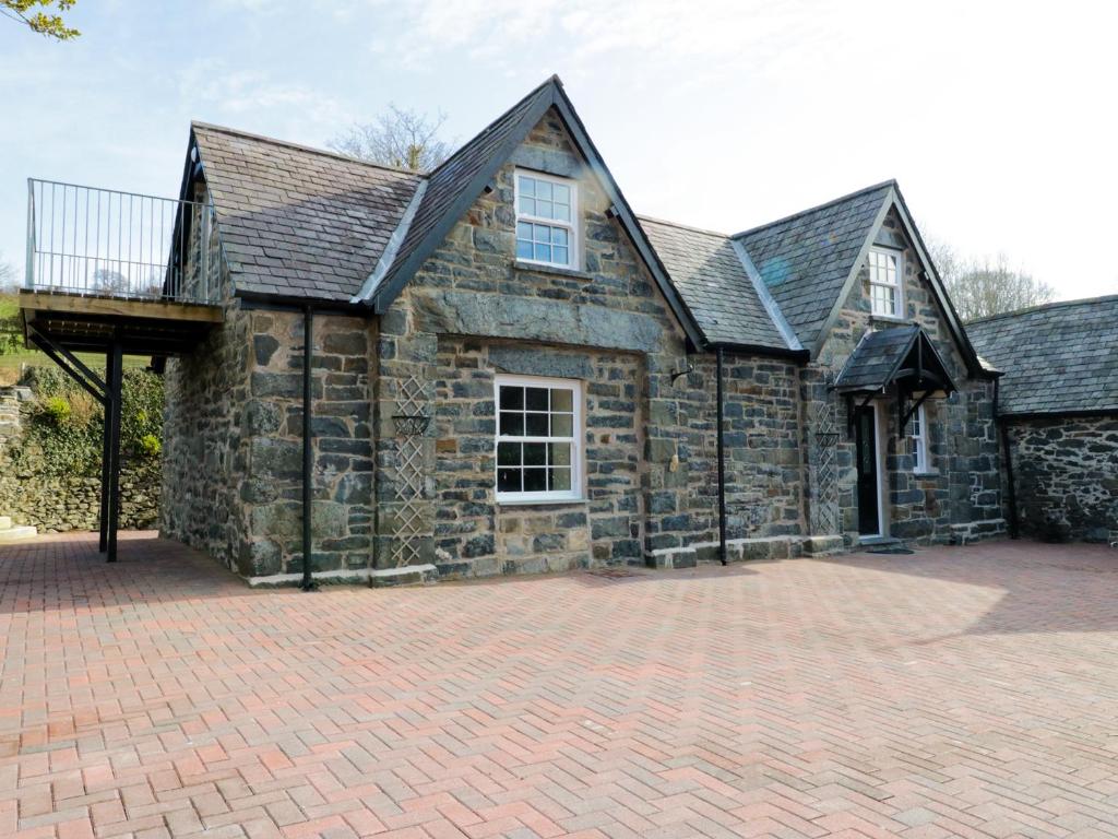 a large stone house with a brick driveway at The Coach House in Llanrwst