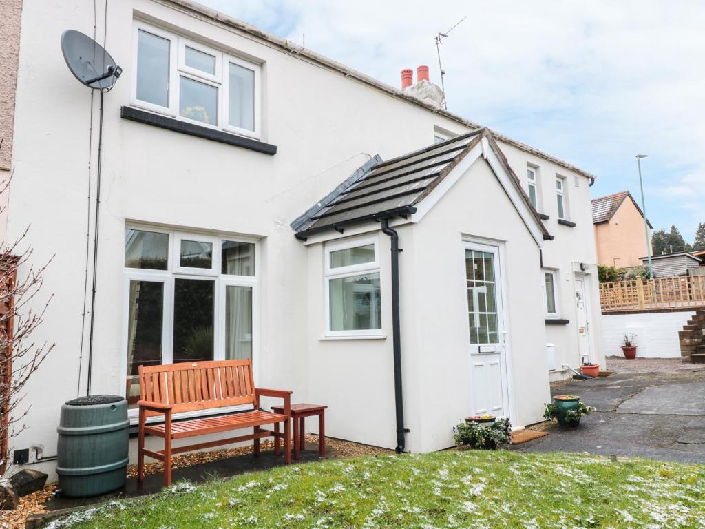 a white house with a bench in the yard at 25 Parragate Road in Cinderford