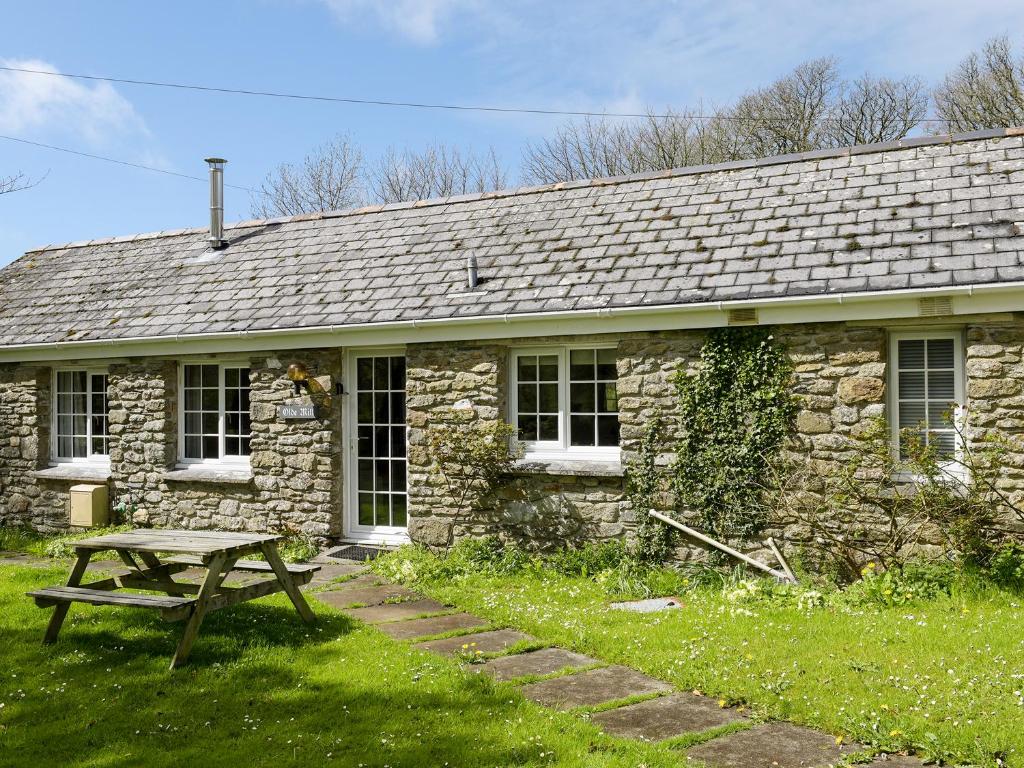 una casa de piedra con una mesa de picnic delante de ella en Old Mill Cottage, en Camelford
