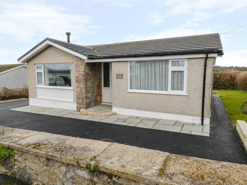 a detached house with a garage and a driveway at Rhos Cottage in Benllech