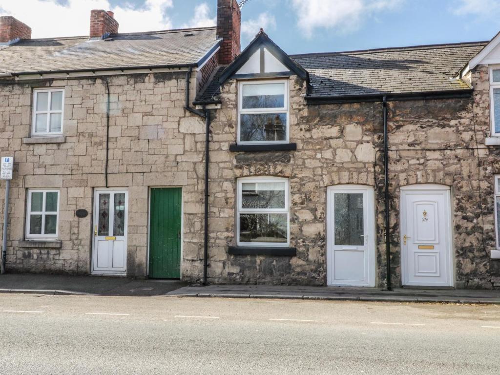 an old stone house with a green door and windows at 27 Borthyn in Ruthin