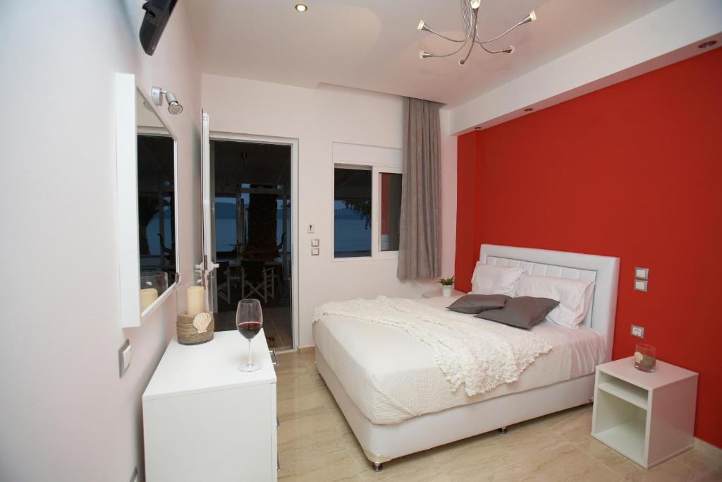 1 dormitorio con cama blanca y pared roja en Ammos Beach en Glífa