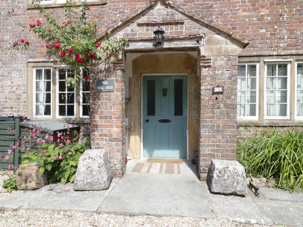 een stenen huis met een blauwe deur en wat bloemen bij Mill House in Dorchester