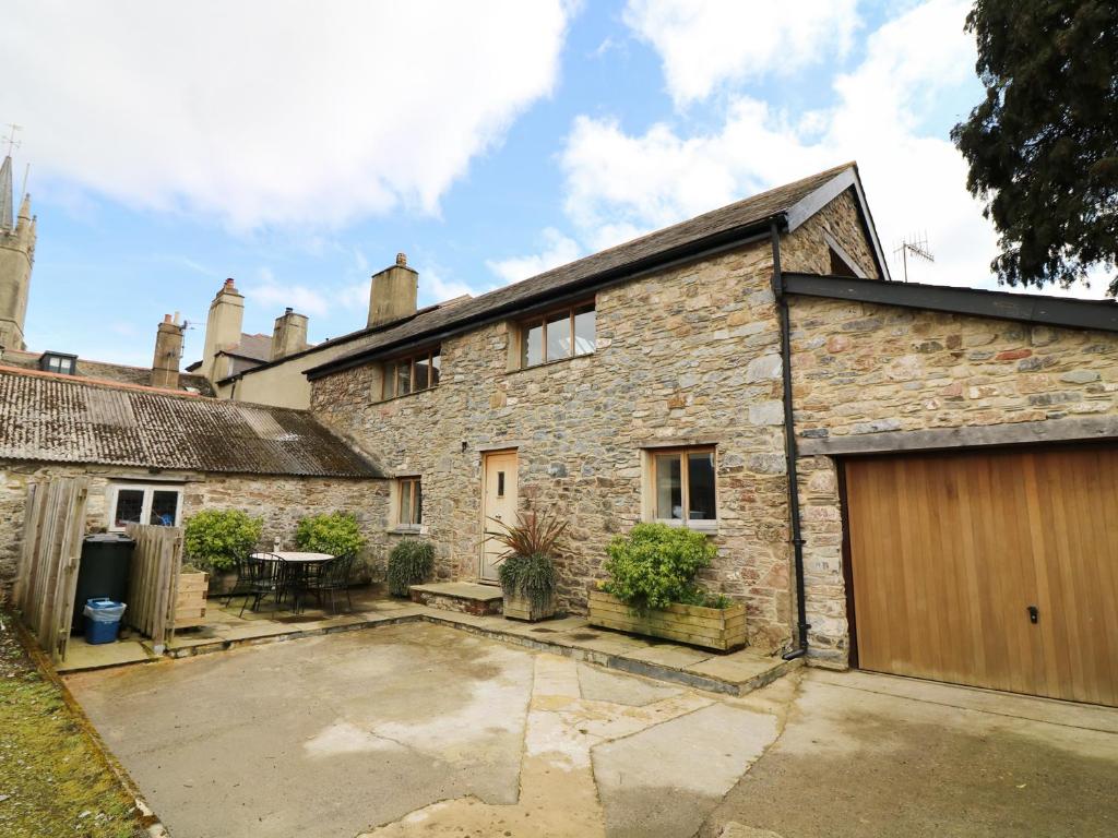 an old stone house with a courtyard in front of it at Old Armoury Barn in Ashburton