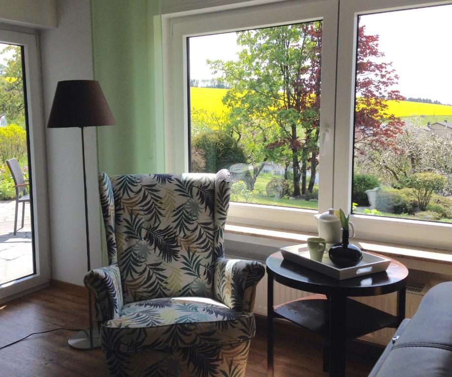 a living room with a chair and a table and windows at Fewo Vulkaneifel in Tettscheid