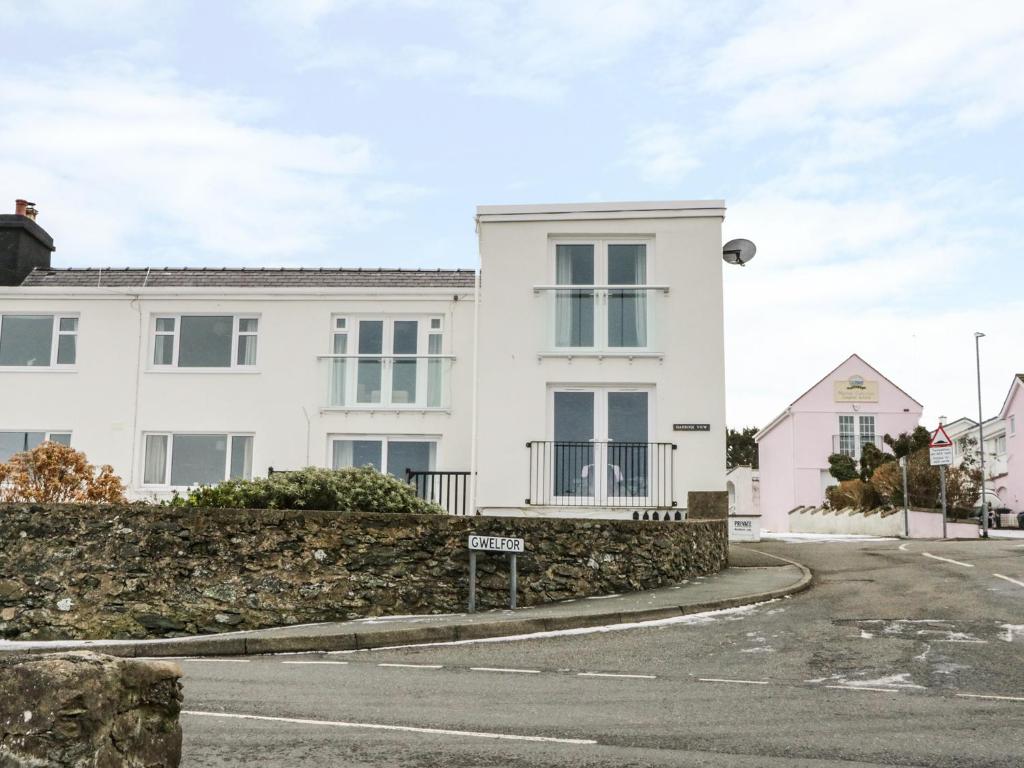 a white house with a stone wall next to a street at Harbour View in Cemaes Bay