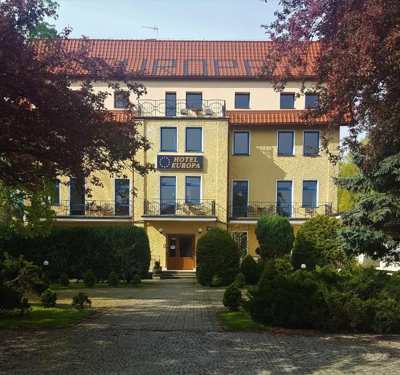 a large yellow building with a driveway in front of it at Hotel Europa in Polanica-Zdrój