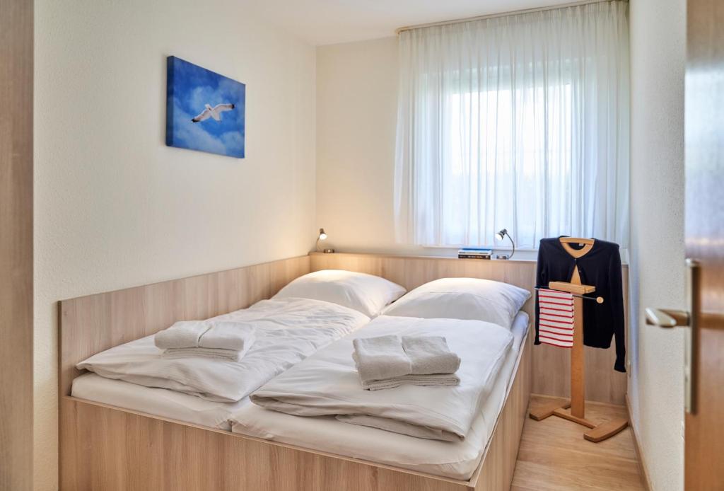 um quarto com uma cama com lençóis brancos em Haus Seemuschel _ Fewo 4 em Cuxhaven