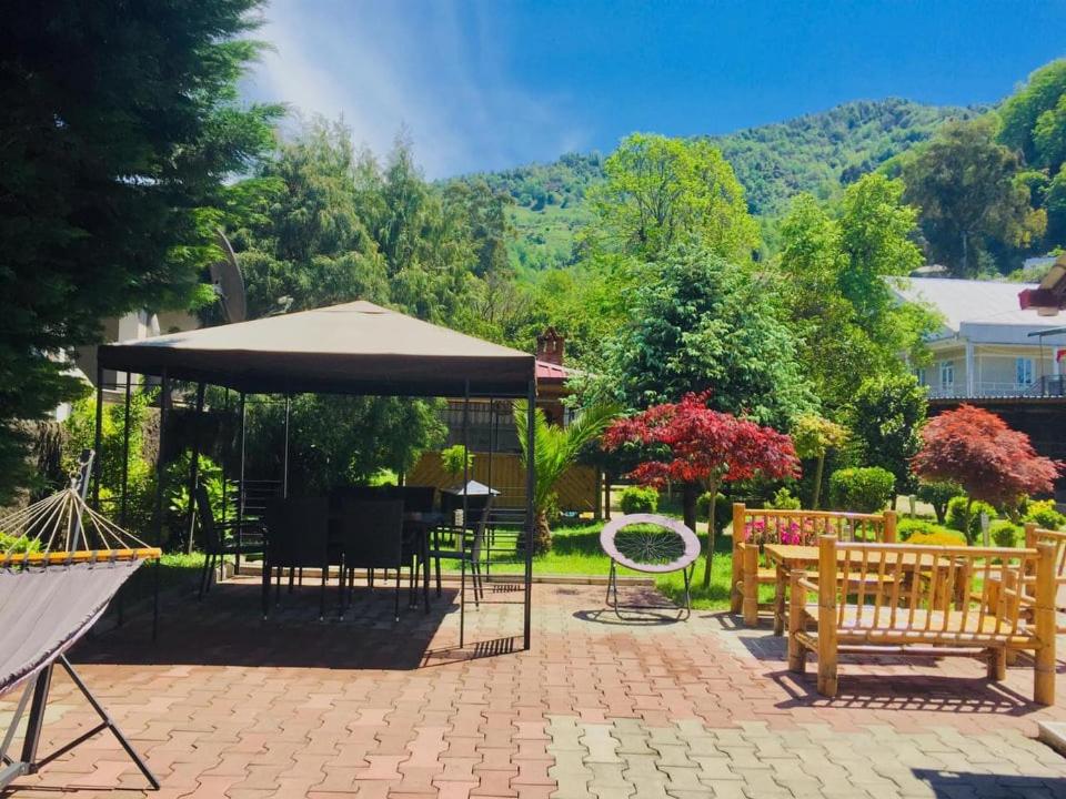 eine Terrasse mit Tischen, Stühlen und einem Sonnenschirm in der Unterkunft Vacation Home Nukri in Gonio