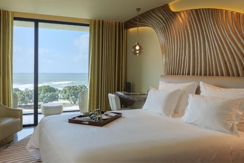 a bedroom with a large white bed with a large window at Vila Foz Hotel & SPA - member of Design Hotels in Porto