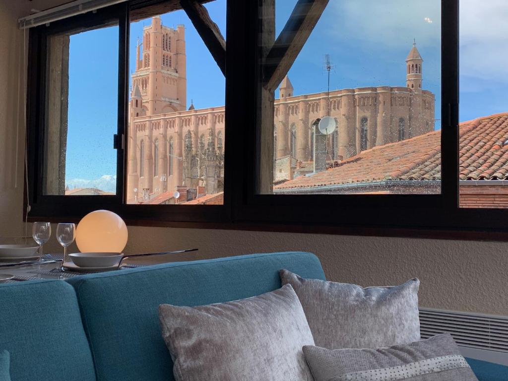 Cette chambre dispose d'un canapé bleu et offre une vue sur un bâtiment. dans l'établissement Cathédrale Appart, à Albi