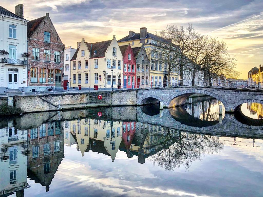 un pont sur une rivière dans une ville avec des bâtiments dans l'établissement Hotel Adornes, à Bruges