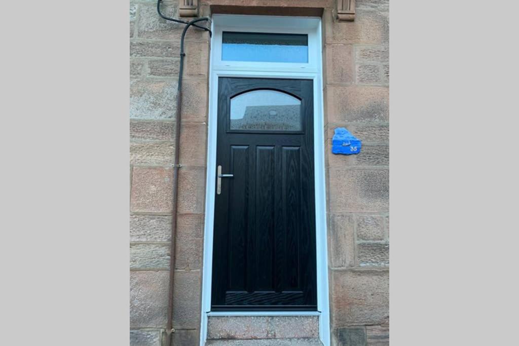 una puerta negra en un edificio de ladrillo con una caja azul en Eyemouth Home by the Harbour en Eyemouth