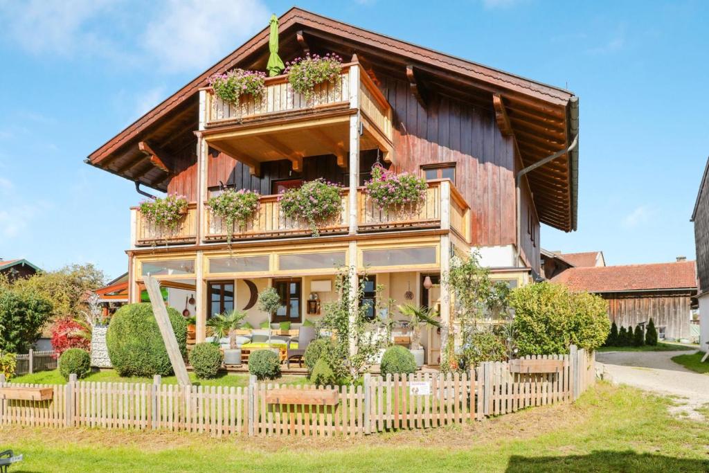 ein Holzhaus mit einem weißen Gartenzaun in der Unterkunft Ferienwohnung Parzinger 2 in Chieming