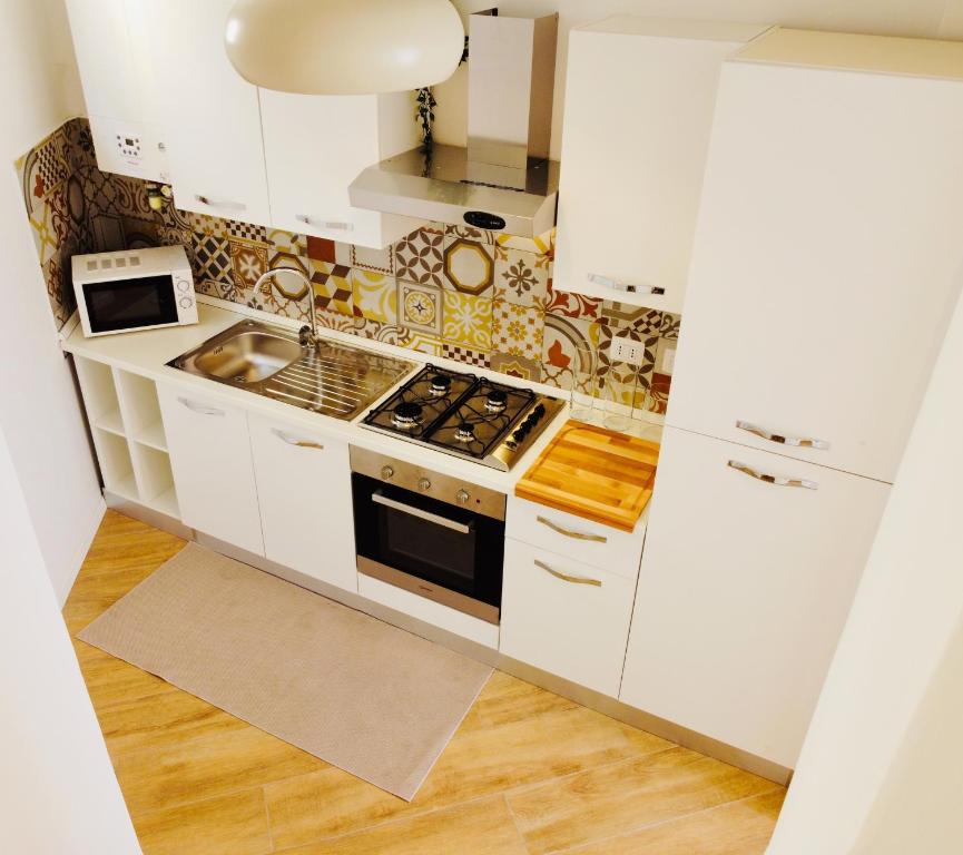 een keuken met witte kasten en een fornuis met oven bij IL NIDO IN CENTRO in La Spezia