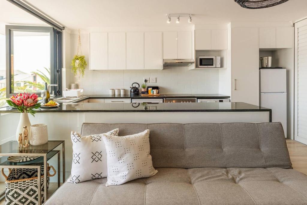 a living room with a couch and a kitchen at MONDAINE CENTRAL LUXURIOUS SPACIOUS AND TRENDY in Cape Town