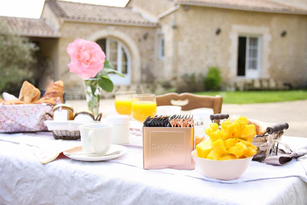 una mesa blanca con comida y bebida y una rosa rosa en Domaine du Moura, en Barsac