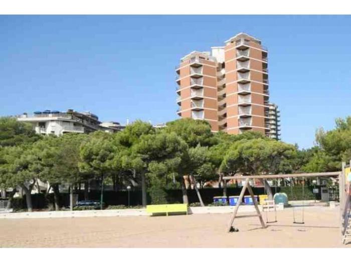 einen Spielplatz in einem Park mit einem hohen Gebäude in der Unterkunft BA - Cristallo - Sea View - in Lignano Sabbiadoro