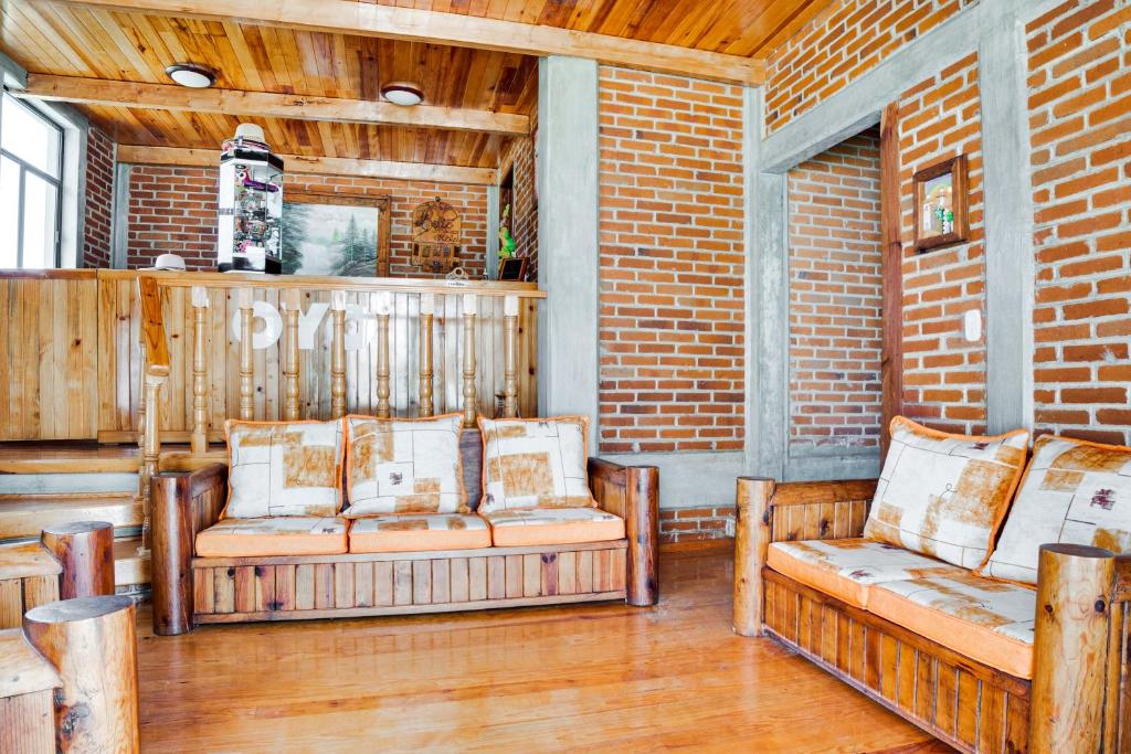 une terrasse couverte avec deux bancs et un mur en briques dans l'établissement Hotel Bello Amanecer, à Mineral del Chico