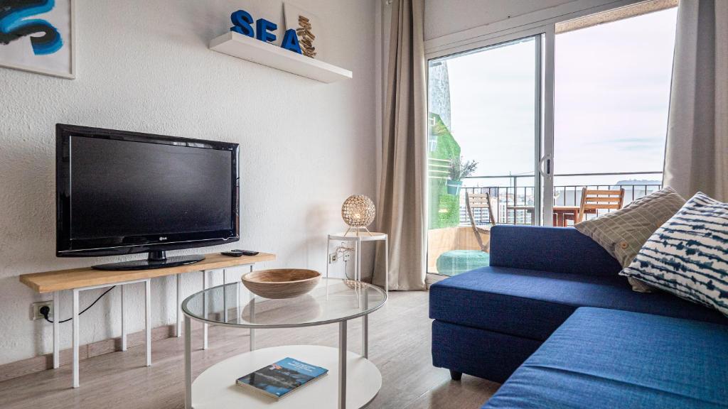 uma sala de estar com um sofá azul e uma televisão em Bed&Bcn Glories em Barcelona