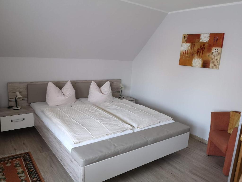 um quarto com uma cama com lençóis brancos e almofadas em Pension Arndt UG em Wangerland