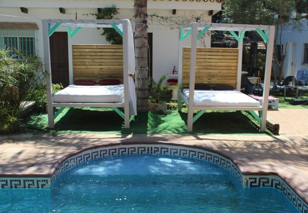 a swimming pool with two chairs and a bed next to a house at Casa Rural Los Pepe Sancti Petri in Chiclana de la Frontera
