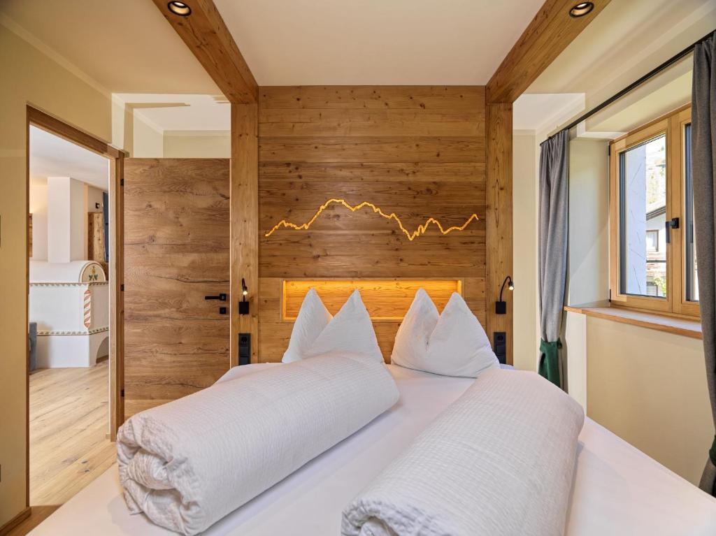 a bedroom with a white bed with a wooden wall at Apartments Riega in Sesto