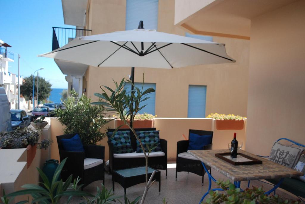 um pátio com uma mesa, cadeiras e um guarda-sol em Apartment Conchiglie 2 em Cala Gonone