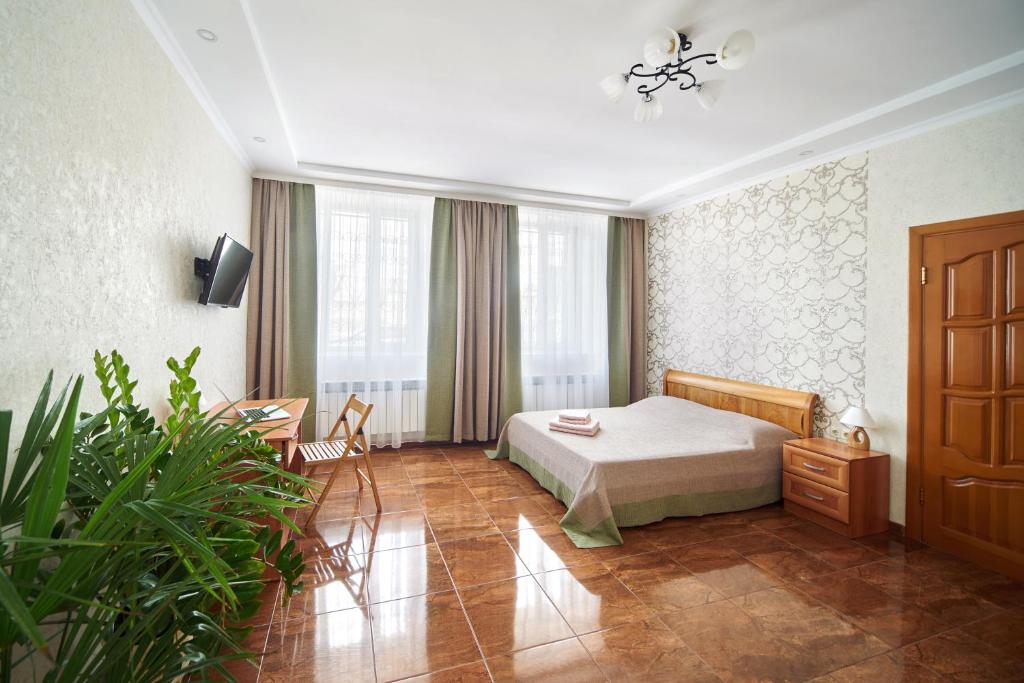 Lyudmila Guest House في سيفاستوبول: غرفة فندقية بسرير وطاولة وكراسي