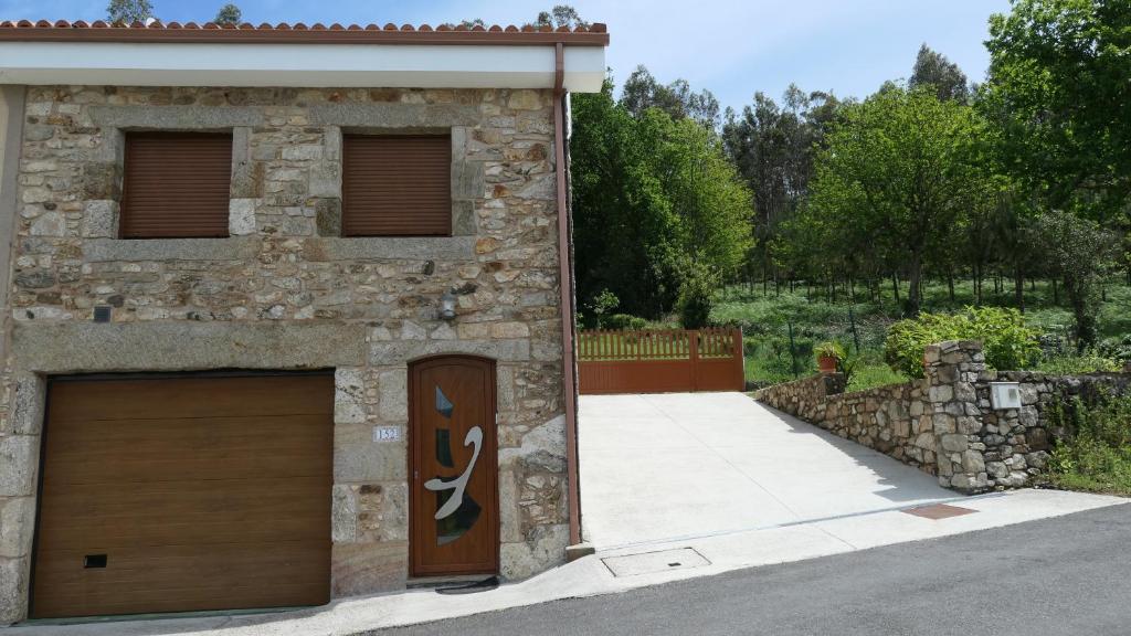 a stone building with two garage doors and a driveway at Casa Leo in Cee