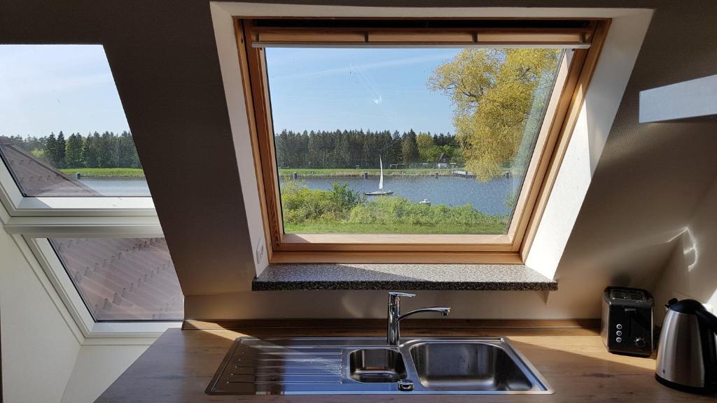 een keuken met een raam boven een wastafel met uitzicht op een meer bij Herrlicher Nord und Süd-Blick direkt am Nord-Ostsee-Kanal in Breiholz