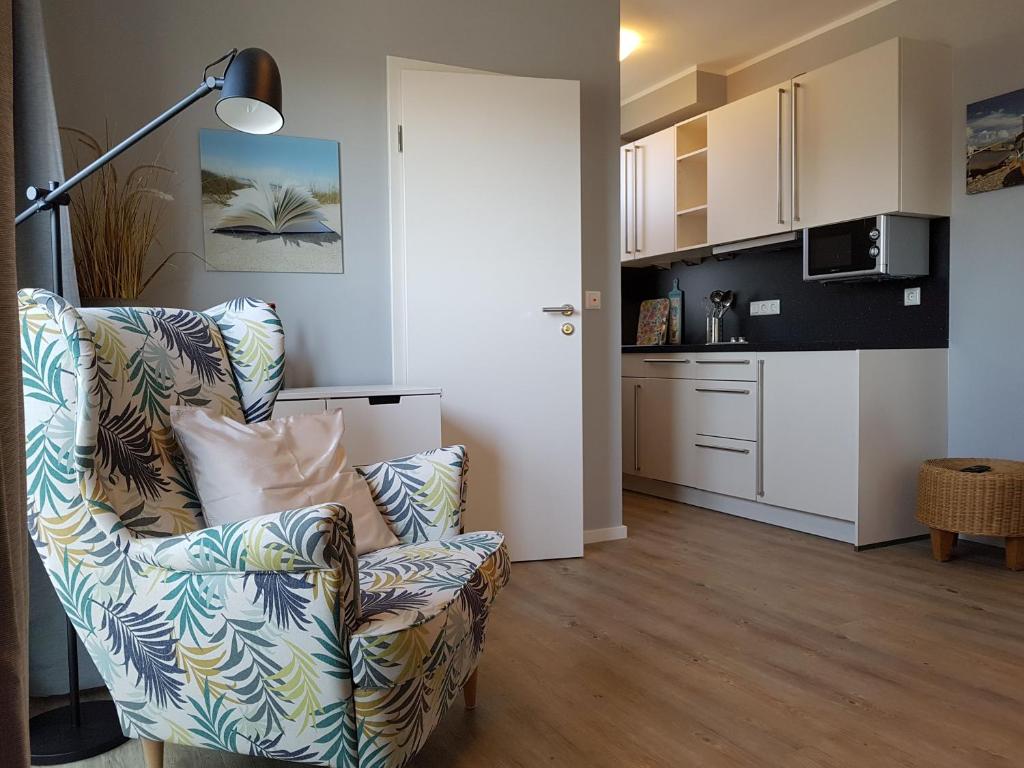 a living room with a chair and a kitchen at Spuren im Sand in Sankt Peter-Ording