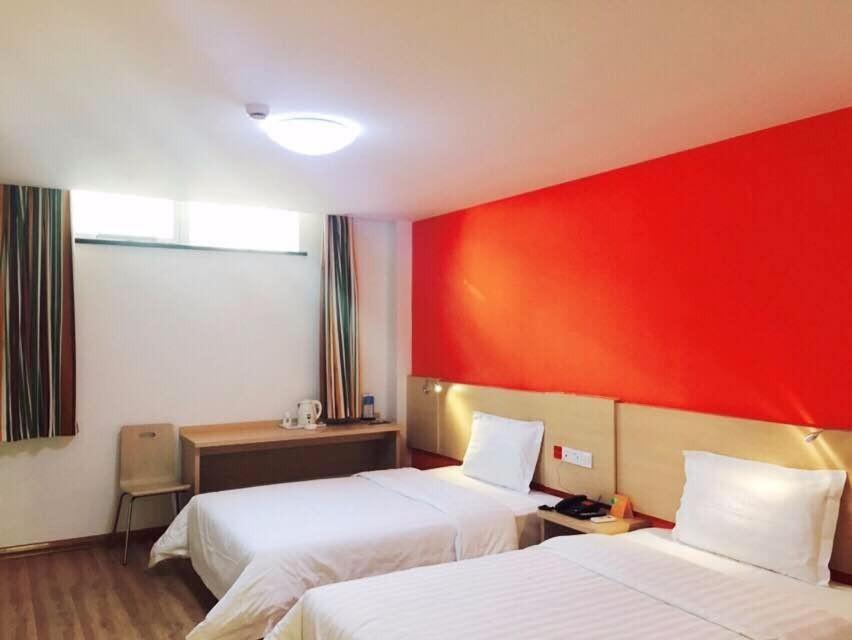 a hotel room with two beds and a red wall at 7Days Inn TianJin Railway Station jinshiqiao Metro Station in Tianjin