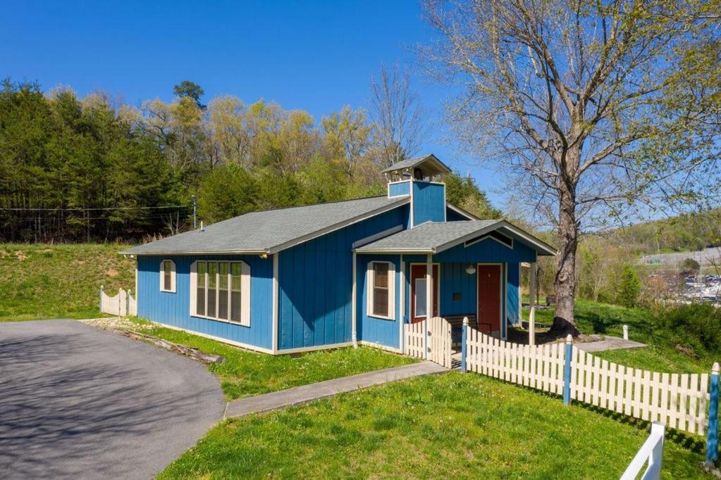 a blue house with a fence in front of it at Across from Dollywood w FREE Dollywood ticket, pets ok wfee, arcade, hot tub in Pigeon Forge