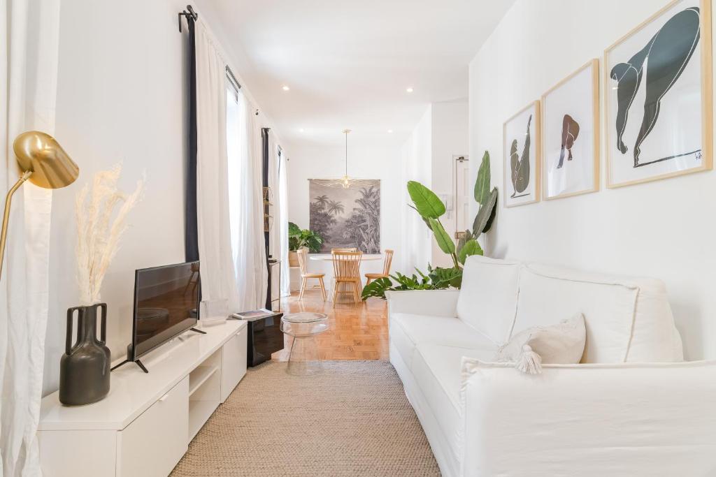 a living room with a white couch and a tv at Casa Boma Lisboa - Spacious and Contemporary Apartment - Campo II in Lisbon