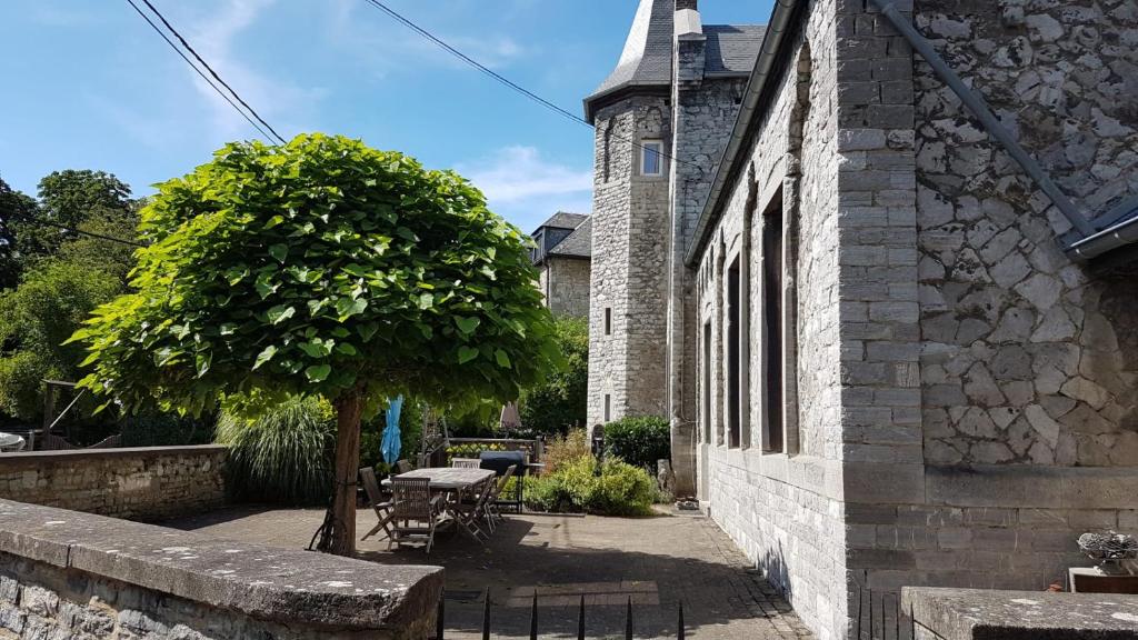 a tree next to a building with a table and a tree at L'Ecole in Dinant