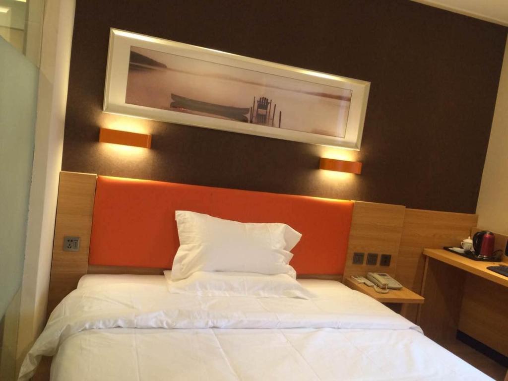 a bedroom with a white bed with an orange headboard at 7Days Premium Nanjing Xinjiekou Zhangfu Garden Metro Station in Nanjing